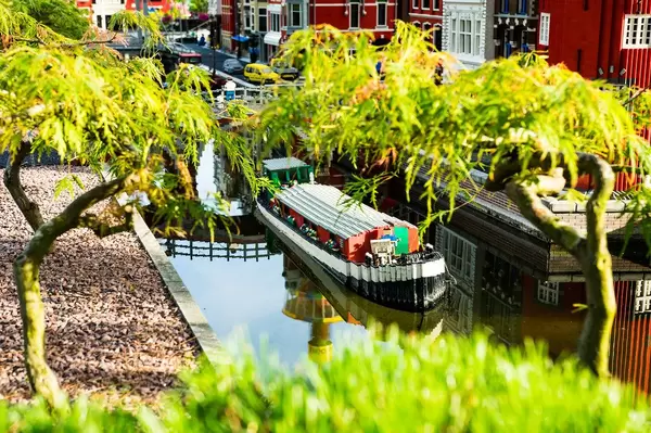 LEGO-Boot fährt in Wasserkanal in aus den Klemmbausteinen gefertigter Stadt