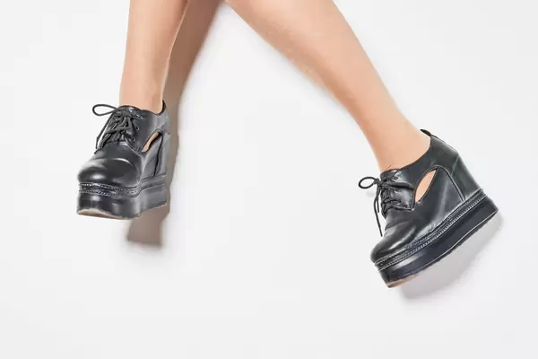 Legs of a young stylish girl wearing leather boots platform