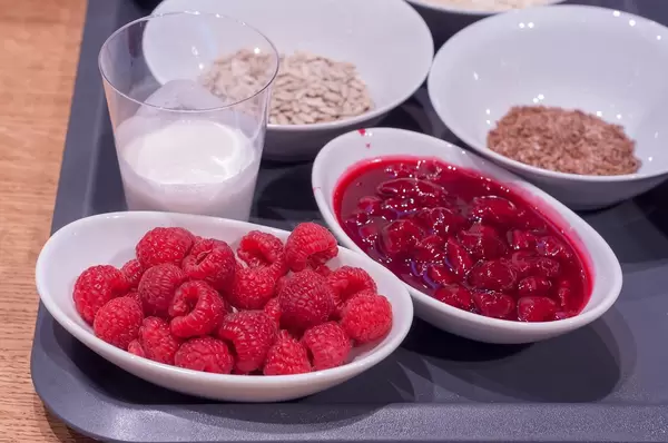 Leichte Kost zum Frühstück: Himbeeren, Kirschmarmelade, Milch, Kerne