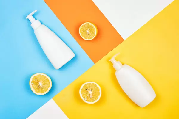 Lemon based shower gel or soap cream bottles on split-colored background