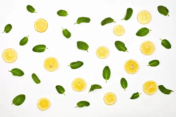 Lemon slices and green leaves on white background