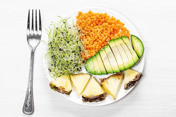 Lentils with micro-green onions, fresh pieces of avocado and pineapple. Top view (Flip 2019)