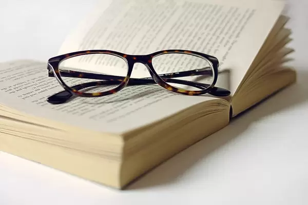 Lesebrille auf aufgeschlagener Romanbuchseite