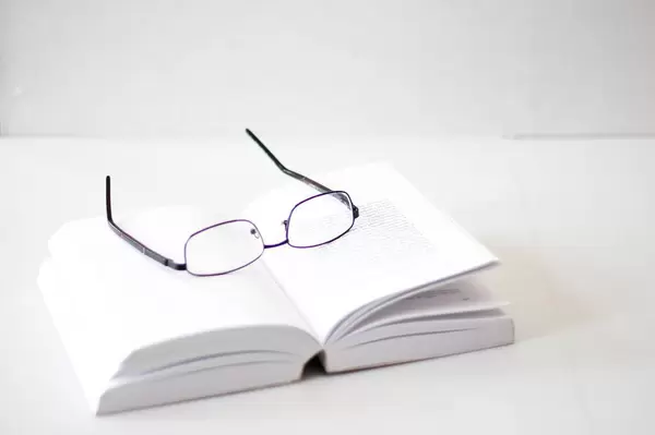 Lesebrille auf einem aufgeschlagenen Buch vor weißem Hintergrund