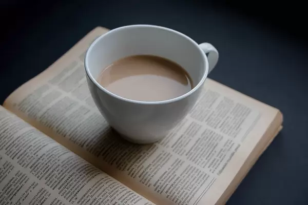 Lesepause: Heißgetränk auf einer aufgeschlagenen Buchseite eines Romans