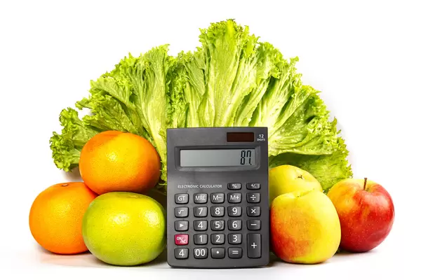 Lettuce, fruits and calculator on a white background, the concept of calories, weight loss and healthy diet