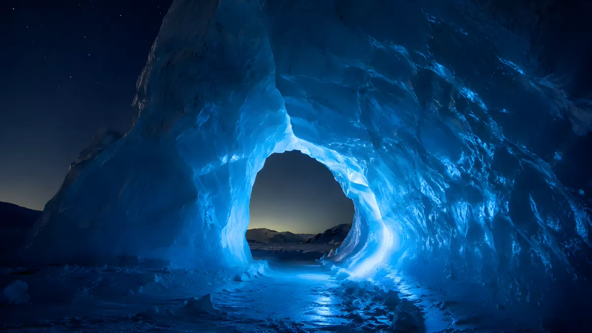 Leuchtende Eishöhle bei Nacht mit Sternenhimmel