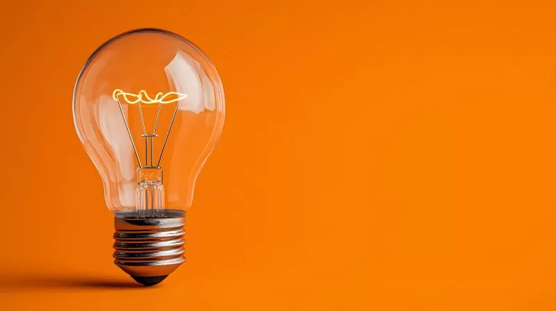 Leuchtende Glühbirne als Idee auf orangefarbenem Hintergrund