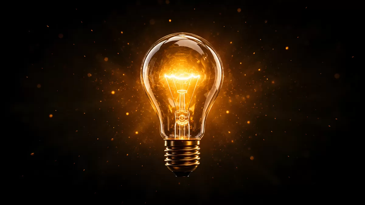 Leuchtende Glühbirne mit goldenem Lichtschein im Dunkeln