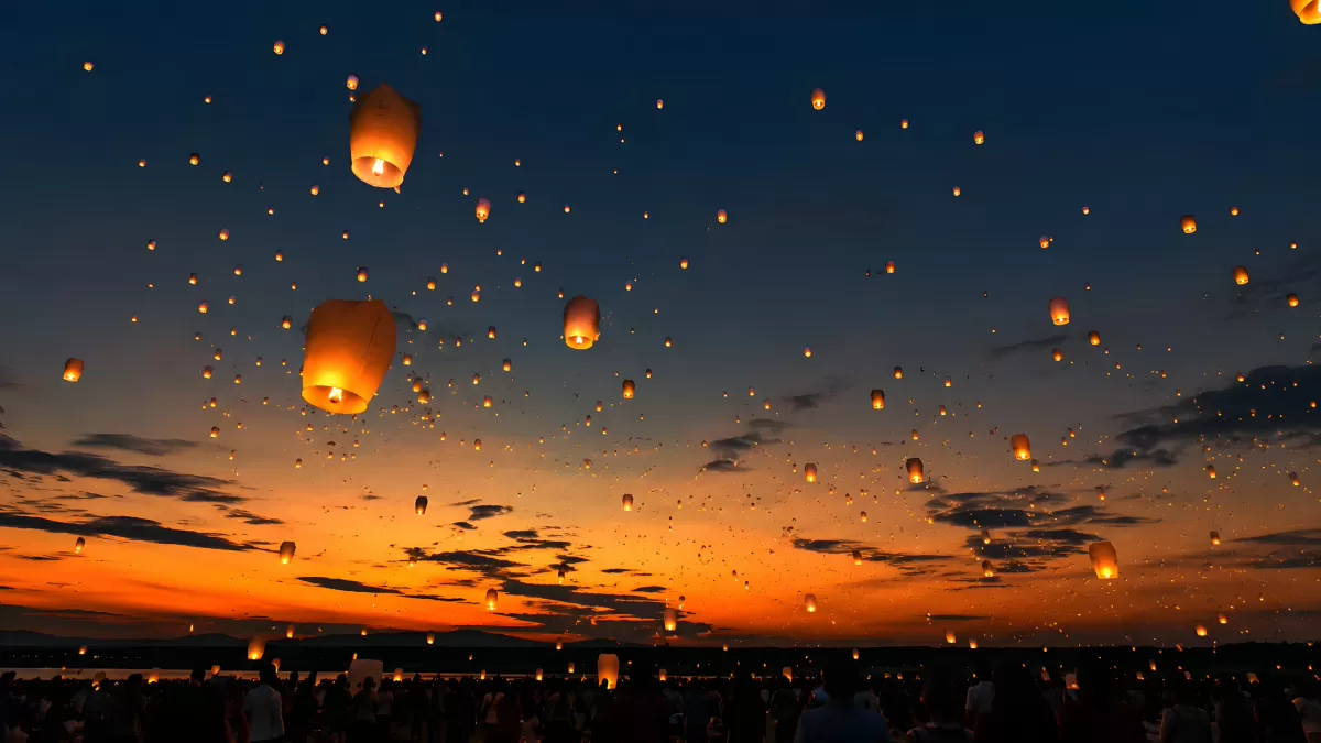 Leuchtende Himmelslaternen steigen bei Sonnenuntergang auf
