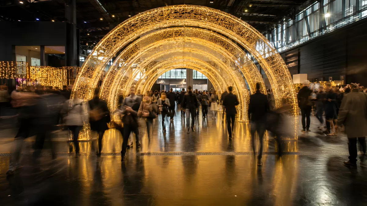Leuchtender Bogentunnel mit Menschen in großer Halle