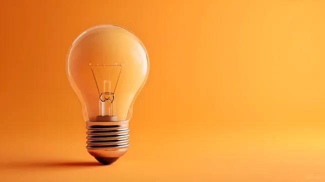 Leuchtkräftige Glühbirne vor orangem Hintergrund