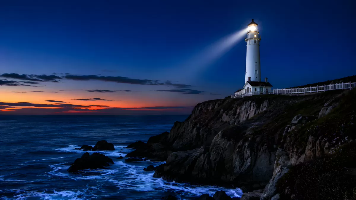 Leuchtturm auf Klippe bei Abenddämmerung am Meer