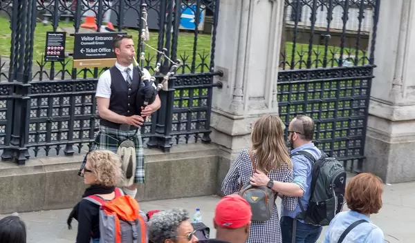 Leute schauen einem Mann zu wie er Dudelsack spielt