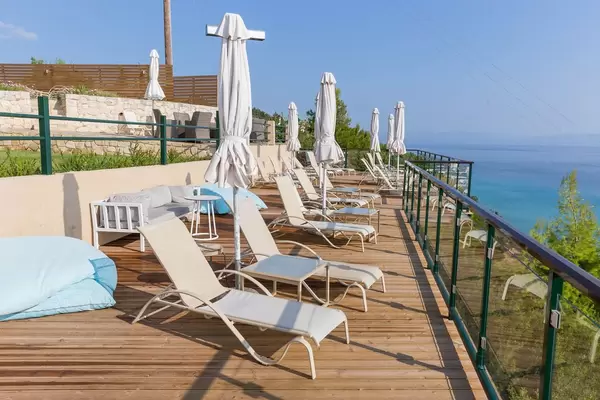 Liegestühle und Sonnenschirme auf einer Hotelterrasse mit Blick aufs Meer