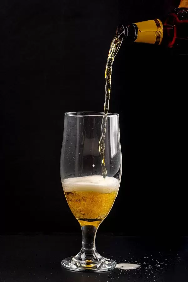 Light beer is poured into a glass on a black background