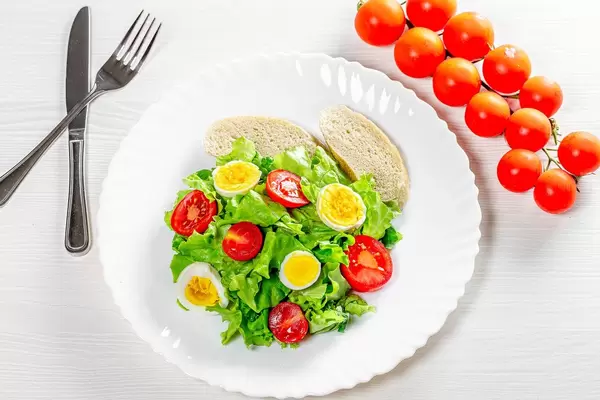 Light salad with herbs, tomatoes, boiled eggs and breadcrumbs on a white table (Flip 2019)
