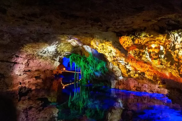 Lighting show at the "Sea of Venice" underground lake, Mallorca, with stalactites illuminated in green