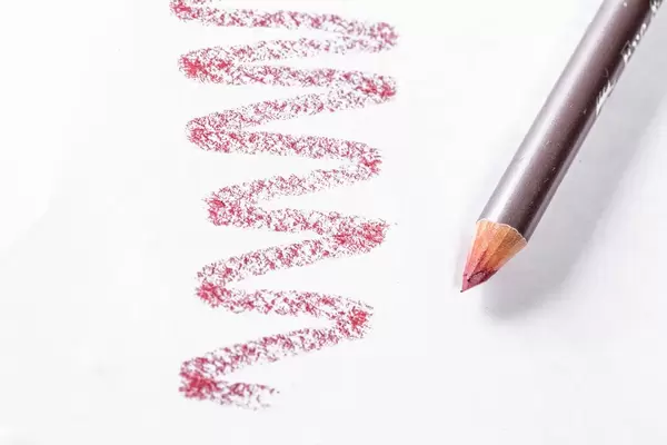 Lippenkonturstift in dezentem Dunkelrot mit Farbprobe auf weißem Papier