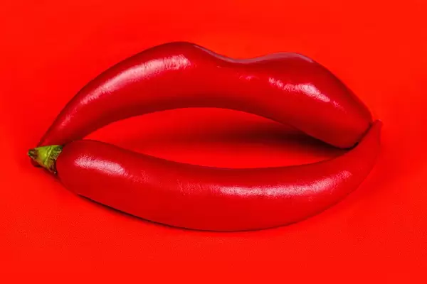Lips made from hot chili peppers on a red background