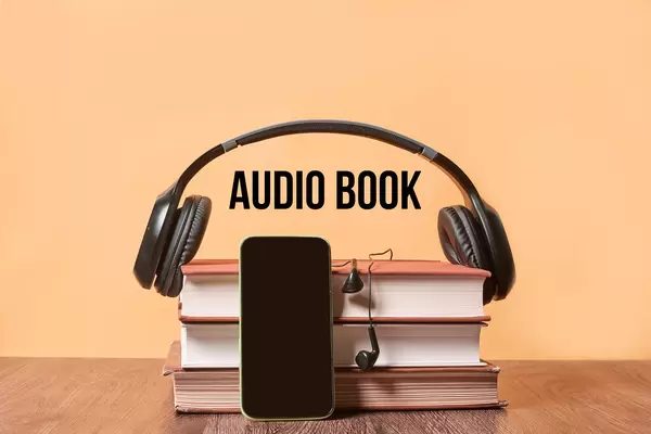 Listening audiobook - Stack of books, mobile phone with empty screen and headphones