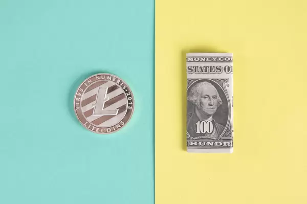 Litecoin coin and folded one hundred dollar banknote