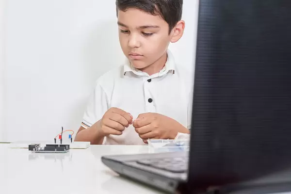 Little boy in robotics school makes robot managed from the constructor