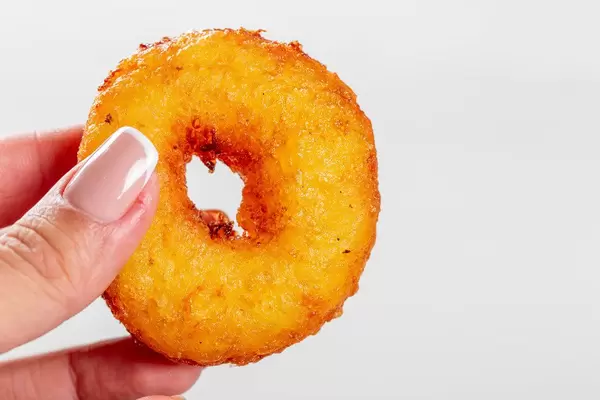 Little fried donut in hand in woman