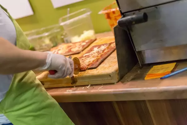 Lizza Low-Carb Pizza wird in kleine Stücke geschnitten