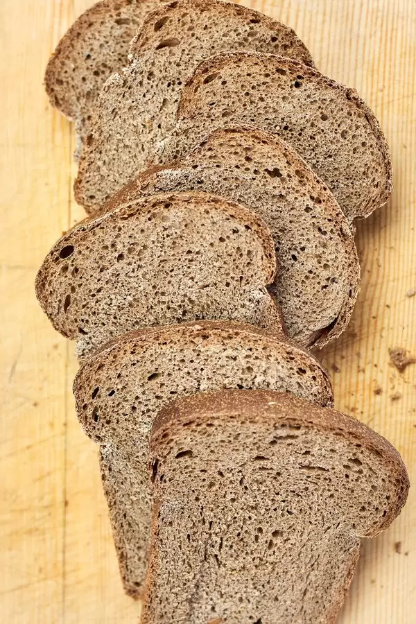 Loaf of sliced wheat bread on cutting board
