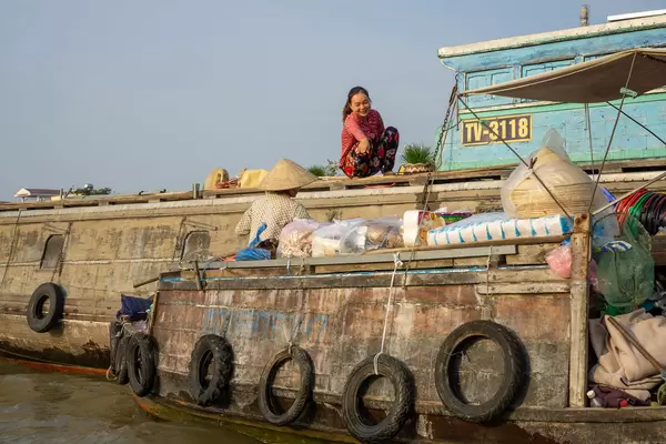 Local Woman pointing at Goods on a Boat Shop from a larger Ship at Cai Rang Floating Market in Can Tho, Vietnam