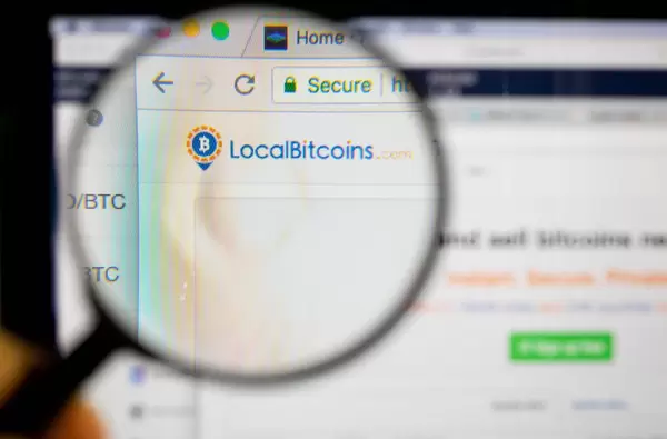 Localbitcoins-Logo am PC-Monitor, durch eine Lupe fotografiert