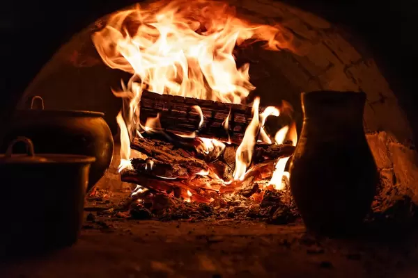 Loderndes Feuer in steinernem Ofen mit Töpfen