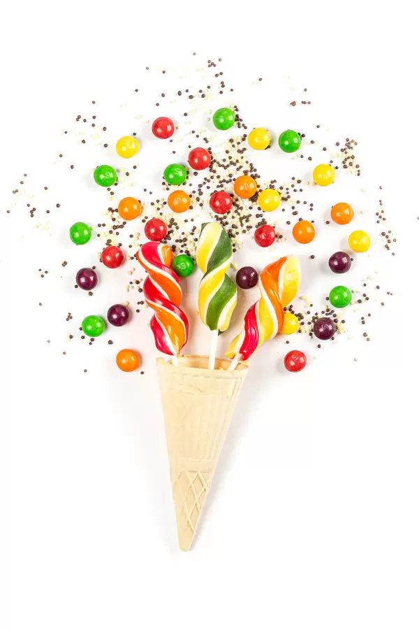 Lollipops in waffle cone and multicolored chocolate candies on white background
