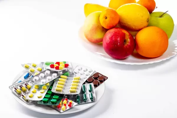 Lots of colorful pills and fresh fruit on white background (Flip 2019)