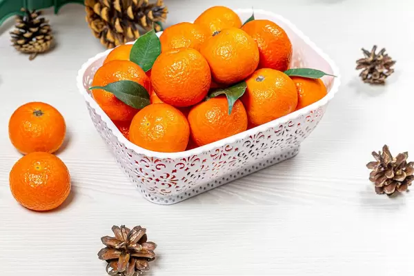 Lots of fresh tangerines on white wooden background with cones (Flip 2019)
