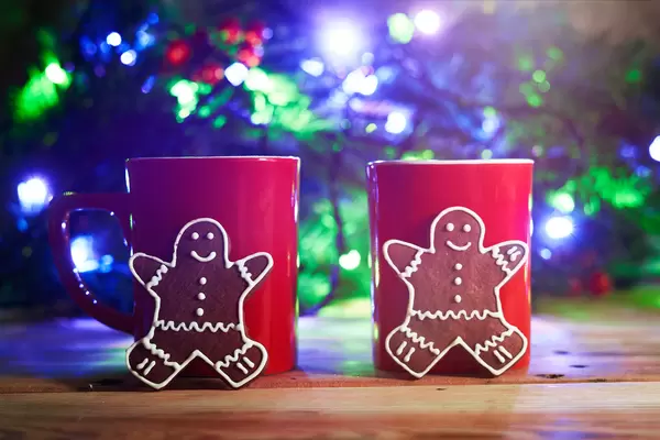 Love in Christmas. Two cups of coffee and festive cookies over the Christmas tree background