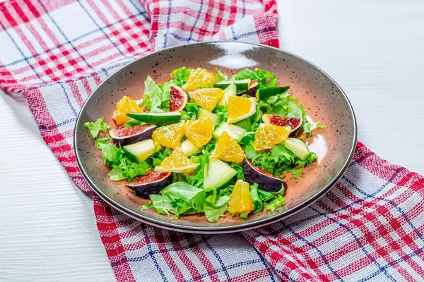 Low-calorie salad with fresh lettuce, oranges, figs and mango. The concept of vegetarianism, weight loss (Flip 2019)