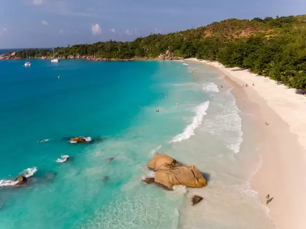 Luftaufnahme der Bucht Anse Lazio mit braunen Granitfelsen am weißen Sandstrand und türkis-blauem Wasser auf Praslin, Seychellen