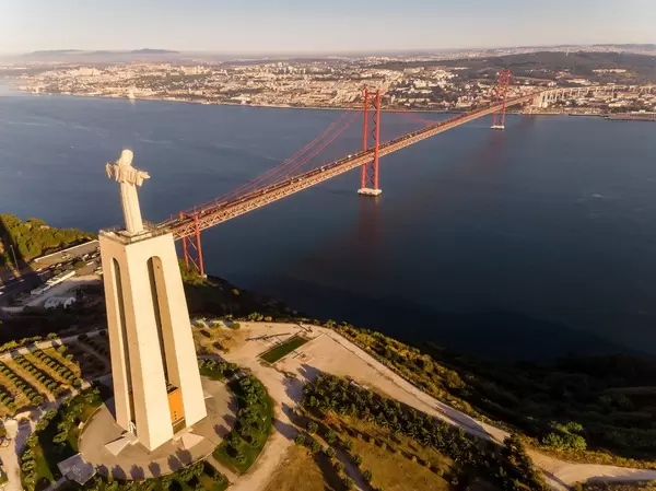 Luftaufnahme der Cristo Rei Statue über den Tajo auf Lissabon blickend mit Ponte 25 de Abril Brücke