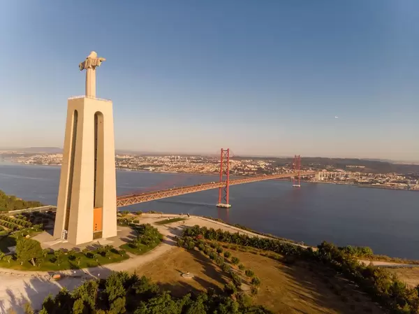 Luftaufnahme der Cristo Rei Statue und der Ponte 25 de Abril Brücke von der Seite in Almada Lissabon