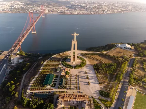 Luftaufnahme der Cristo Rei Statue von hinten mit Ponte 25 de abril Brücke