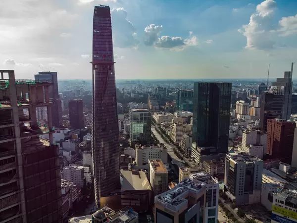 Luftaufnahme der Nguyen Hue Fußgängerzone und Bitexco Financial Tower neben der verlassenen Baustelle vom Saigon One Tower in Ho Chi Minh Stadt, Vietnam