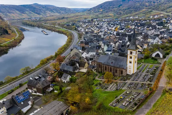 Luftaufnahme der Ortsgemeinde Bremm im Landkreis Cochem-Zell in Rheinland-Pfalz mit Wohngebäude, St. Laurentius-Kirche, dem Fluss Mosel und Bundesstraße B49