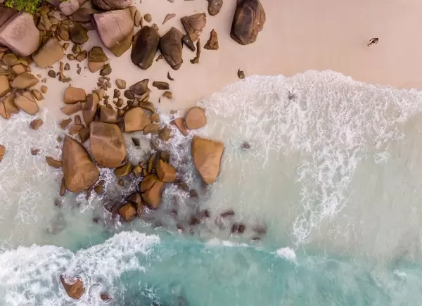 Luftaufnahme des Anse Lazio Strands im Norden von Praslin (Seychellen), mit türkisblauem Meer und Granitsteinen