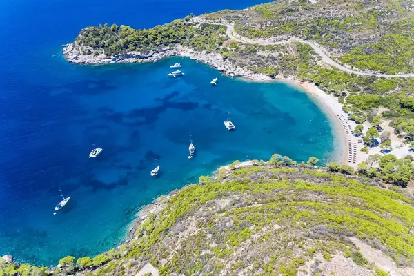 Luftaufnahme mit Blick von der steilen Küste, zu teuren Jachten in der Meeresbucht am Plaza Paraskevi Strand