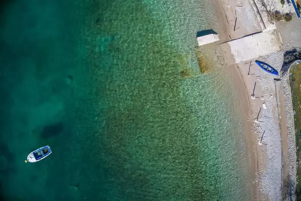 Luftaufnahme mit der Drohne von einem Kiesstrand und türkisblauem Wasser