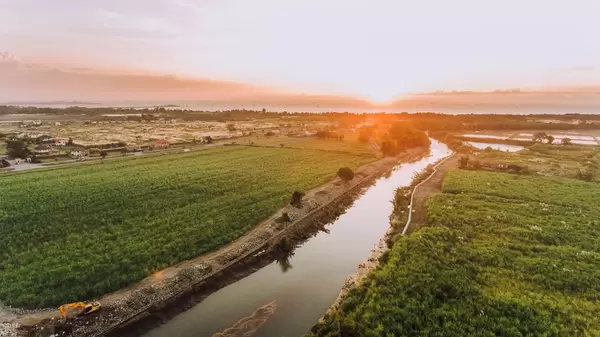 Luftaufnahme mit der Drohne von Plantagen bei Sonnenuntergang an einem Fluss gelegen