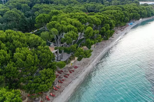 Luftaufnahme: Playa de Formentor auf Mallorca mit braunen Sonnenliegen und Strohsonnenschirmen