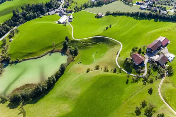 Luftaufnahme von grüner Landschaft mit Bäumen, Häusern und dem Frauensee mit hellgrünem Wasser